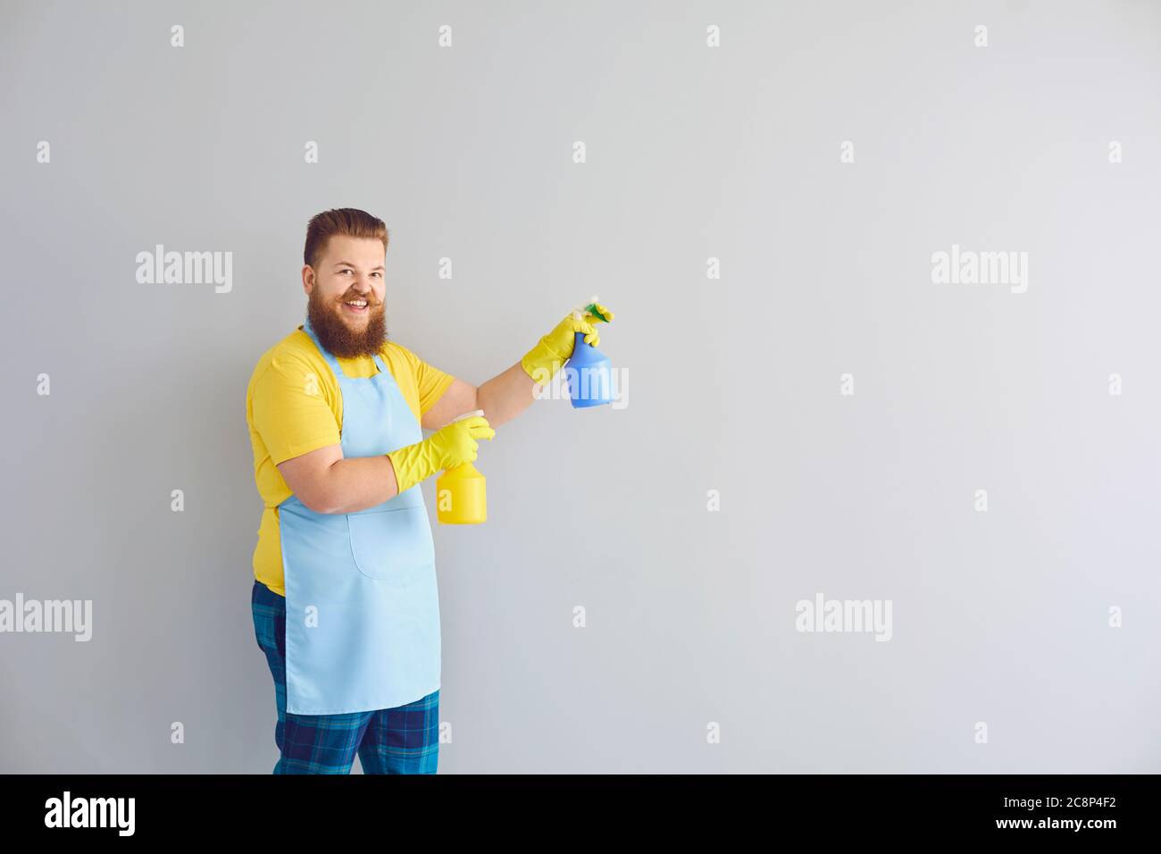 Reinigungsservice und Hausarbeit Konzept. Glücklich lustigen Kerl mit Waschmitteln auf grauem Hintergrund, Platz für Text Stockfoto