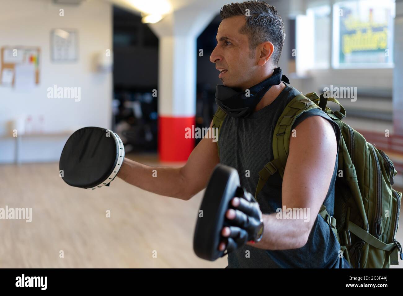 Motivierter Boot Camp Trainer steht mit Schlagschuhen in der Turnhalle. Training mit verlängertem Arm auf Holzboden. Portrait für Fitness-Konzept. Stockfoto