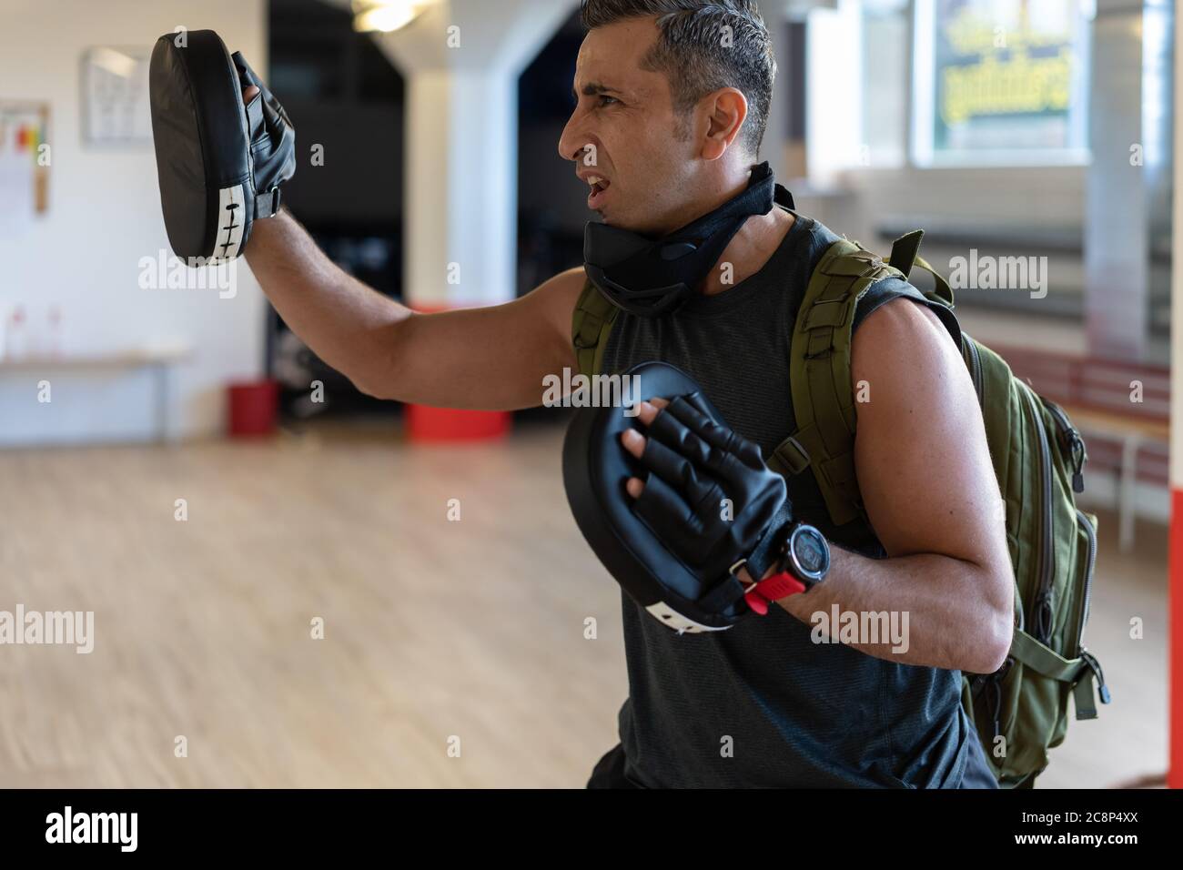 Motivierter Boot Camp Trainer steht mit Schlagschuhen in der Turnhalle. Training mit verlängertem Arm auf Holzboden. Portrait für Fitness-Konzept. Stockfoto