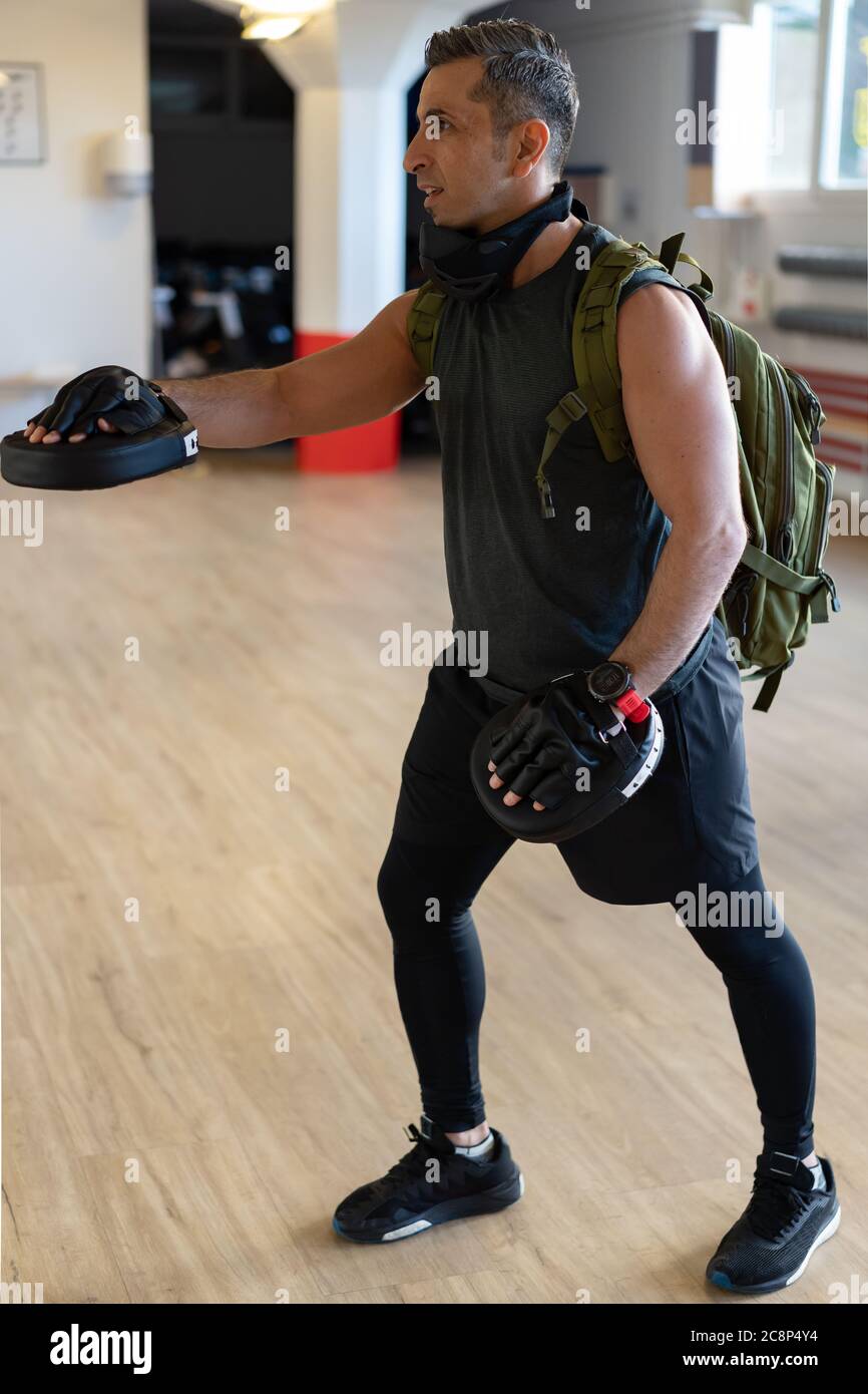 Motivierter Boot Camp Trainer steht mit Schlagschuhen in der Turnhalle. Training mit verlängertem Arm auf Holzboden. Portrait für Fitness-Konzept. Stockfoto