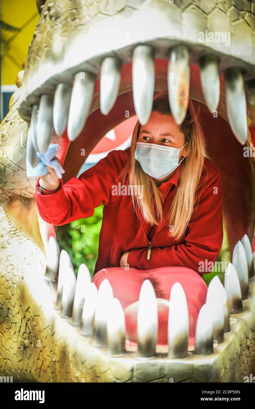 26. Juli 2020, Brecon Beacons, Wales. Mitarbeiter Elisha Lewis reinigt das Innere eines Dinosauriermaul in Dan-yr-Ogof Caves in Wales. Die Attraktion, die den größten Höhlenkomplex ihrer Art in Großbritannien hat und sich im Brecon Beacons National Park befindet, hat dieses Wochenende nach monatelanger Schließung aufgrund der Coronavirus-Sperre wieder eröffnet. Ähnliche Attraktionen in England, die seit einem Monat geöffnet sind, drängten die walisische Regierung, diesem Beispiel zu folgen und Dan-yr-Ogof ihre Türen öffnen zu lassen. Kredit : Robert Melen/Alamy Live Nachrichten. Stockfoto