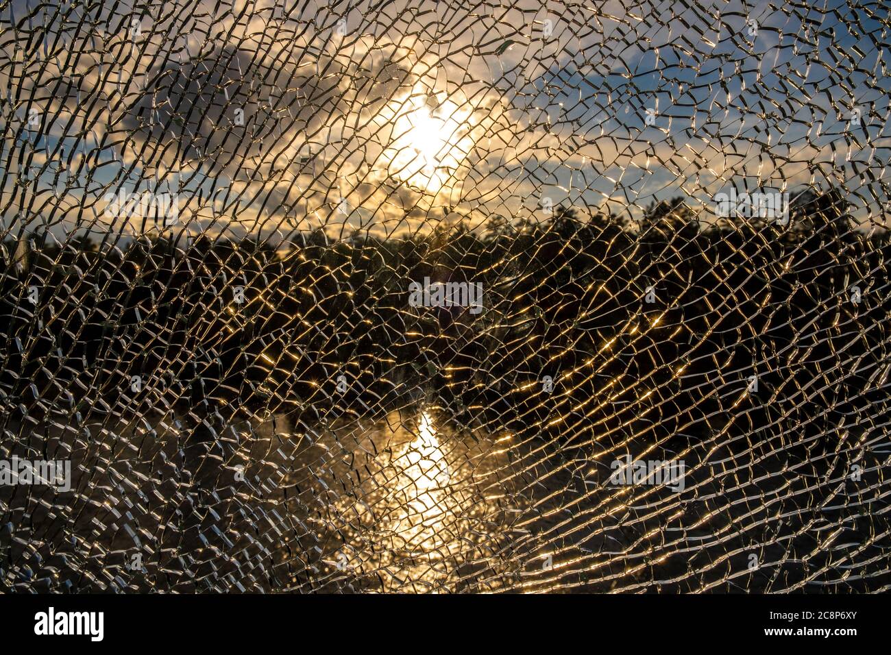 Landschaft mit der untergehenden Sonne und ihrer Reflexion im Fluss durch gebrochenes Glas. Die unscharfe Erscheinung, die durch die Textur erzeugt wird. Leerzeichen für Text. Stockfoto