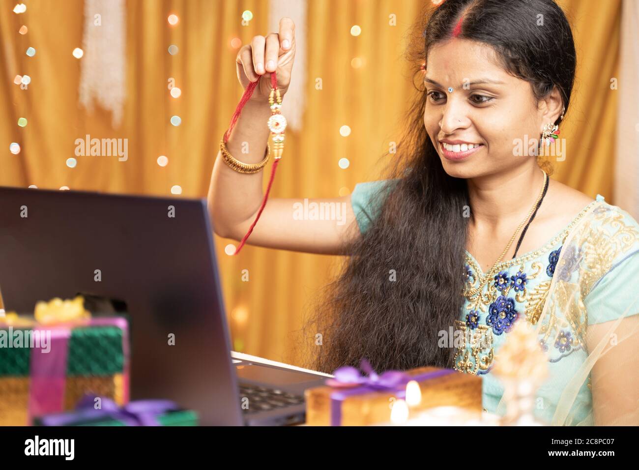 Indische Frau in Tradition Kleid auf Video-Anruf oder Chat auf Raksha Bandhan Festival sagen, ihr Bruder zu Krawatte rakhi - Konzept der Distanz Beziehungen Stockfoto