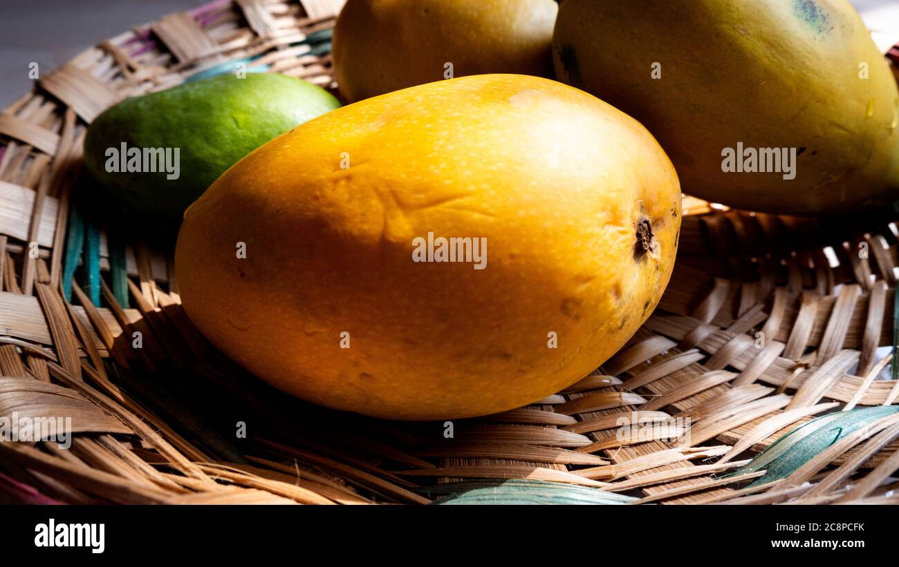 Eine frische saftige Mango isoliert auf Bambus Textur Hintergrund Wasser Tropfen auf Stockfoto