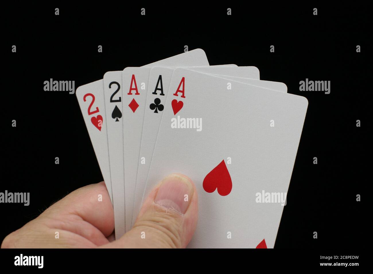 Hand hält Poker Spielkarten auf schwarzem Hintergrund. Stockfoto