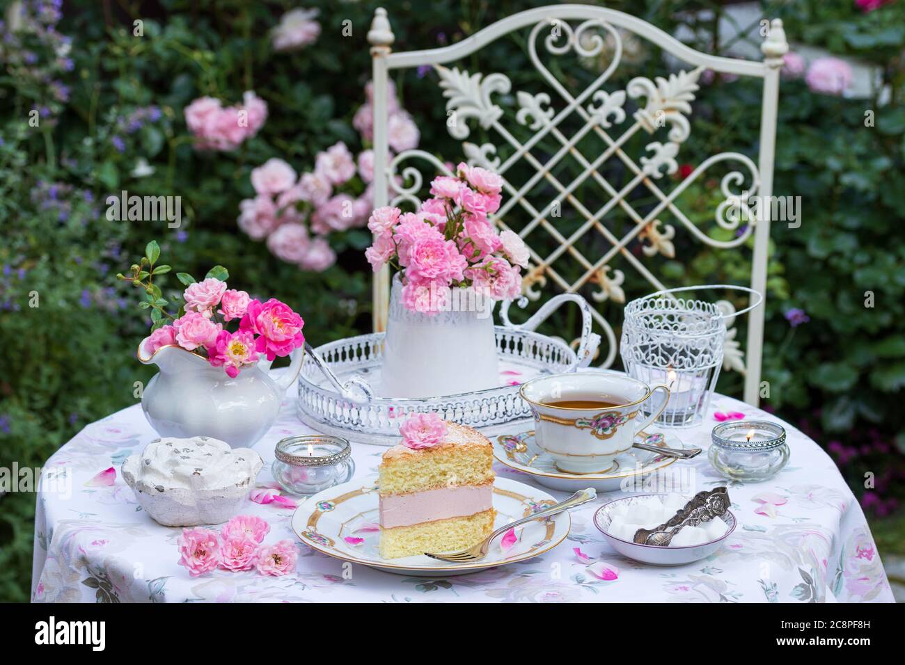 Romantische Tischdekoration mit Cremekuchen, Rosenstrauß und Vintage Porzellan Stockfoto