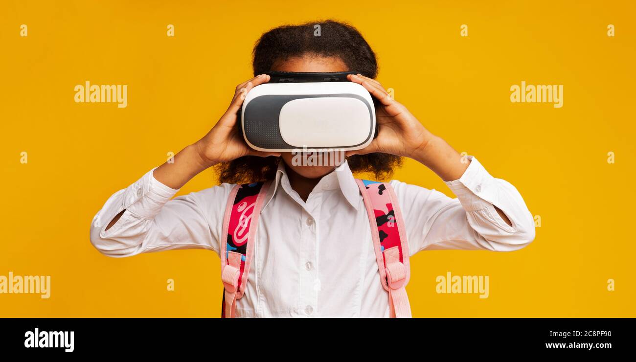 Afrikanische Schulmädchen tragen VR Brille erleben virtuelle Realität, Gelber Hintergrund Stockfoto