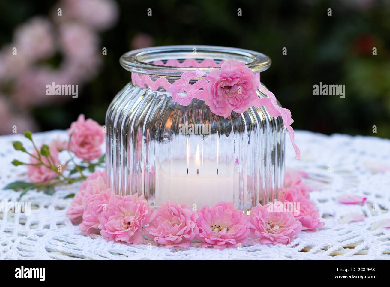 Romantische Gartendekoration mit rosa Rosen und Kerze im Glas Stockfoto