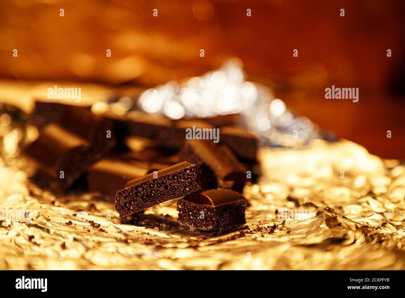 Leckere poröse schwarze Schokoladenstücke auf einer Goldfolie Stockfoto