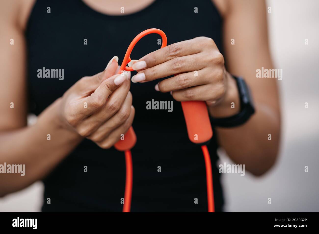 Vorbereitung auf die Schulung. Afroamerikanisches Mädchen mit Fitness-Tracker, verknotete Seil auf Knoten Stockfoto