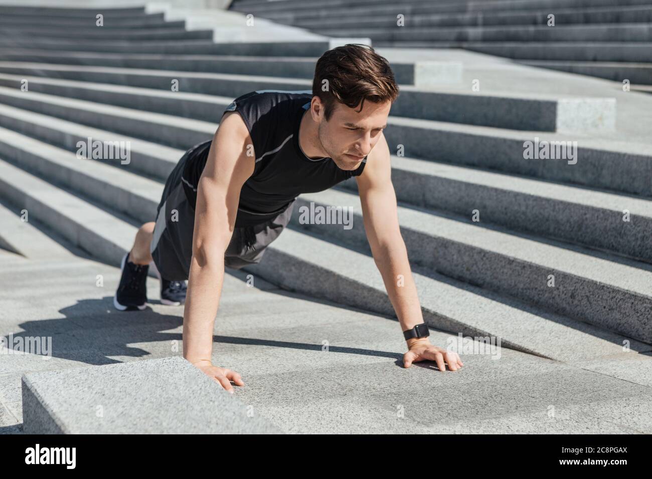 Aktive Freizeit und Motivation. Typ mit Fitness Tracker schieben die Stadttreppe hoch Stockfoto
