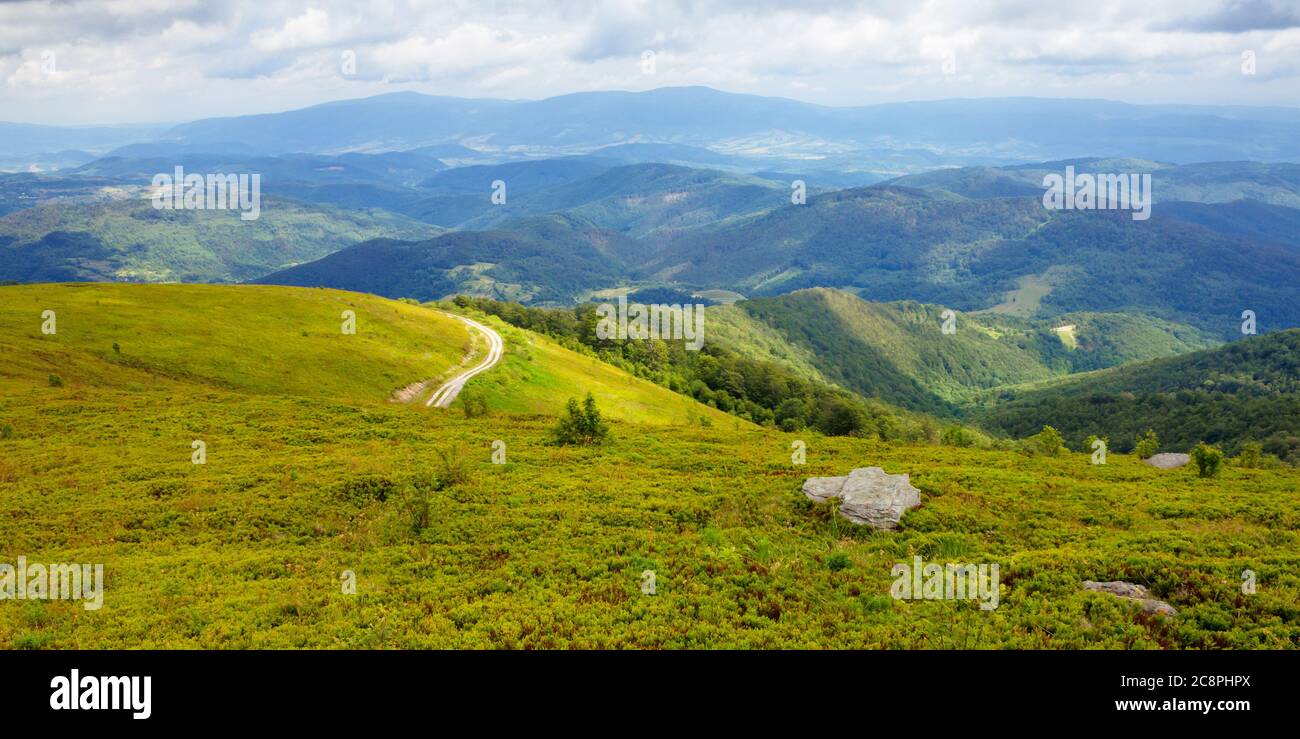 Reisen karpaten im Sommer. Straße durch grüne Wiesen in der Ferne. Idyllische Landschaft mit Wolken am blauen Himmel. Stockfoto