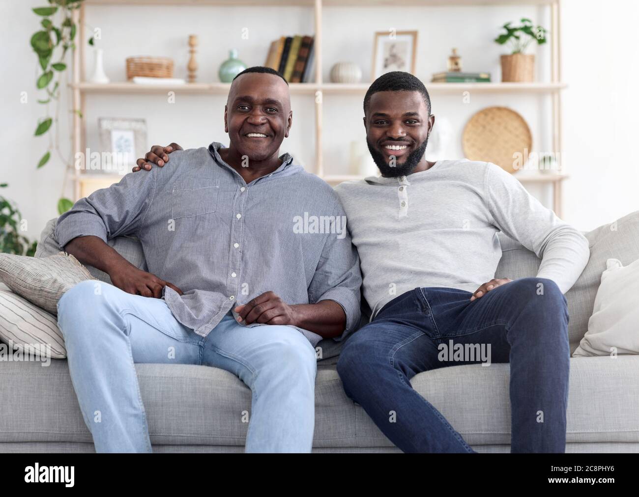 Erwachsene schwarzen Sohn und sein älterer Vater posiert auf Couch zu Hause Stockfoto
