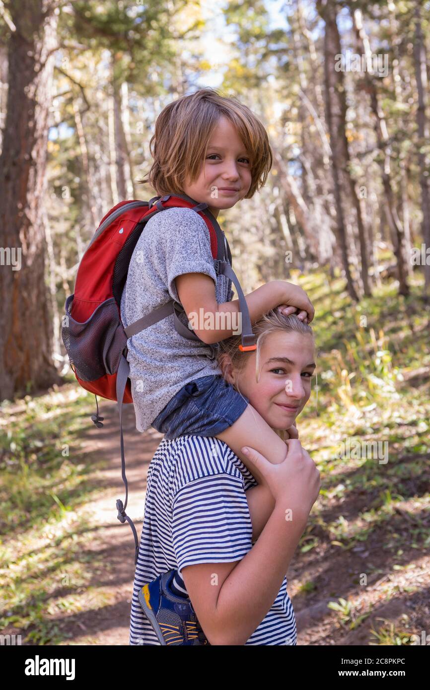 4 Jahre alter Junge, der auf den Schultern der Schwester reiten wird Stockfoto