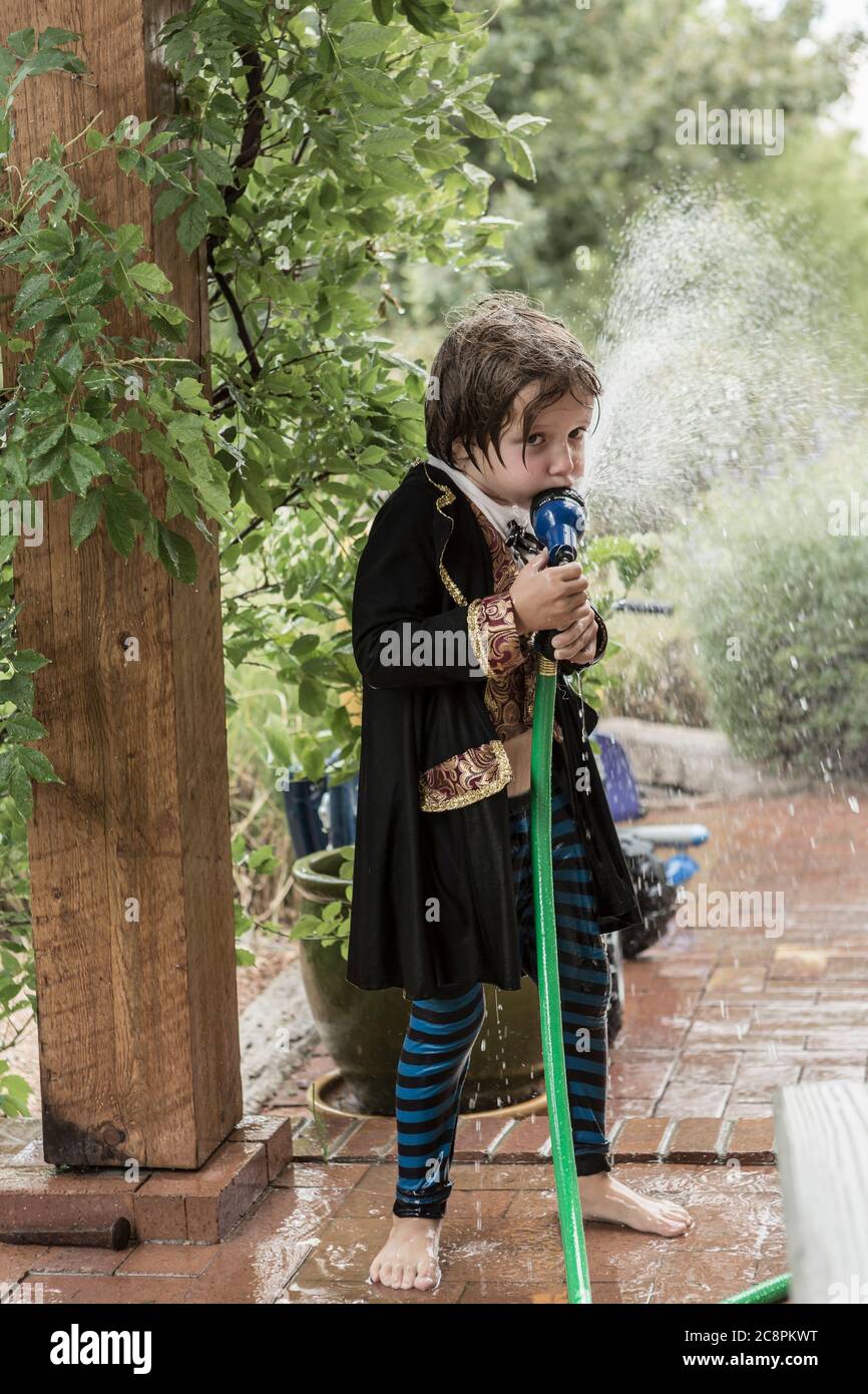 Kleiner Junge, der als Pirat gekleidet ist und aus einem Wasserschlauch trinkt Stockfoto