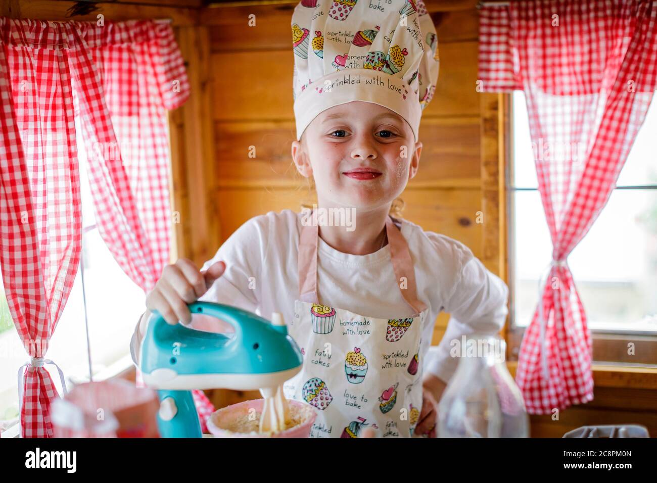 Portrait von jungen Mädchen in Koch-Outfit in wendy Haus gekleidet vorgeben, in der Küche zu kochen Stockfoto