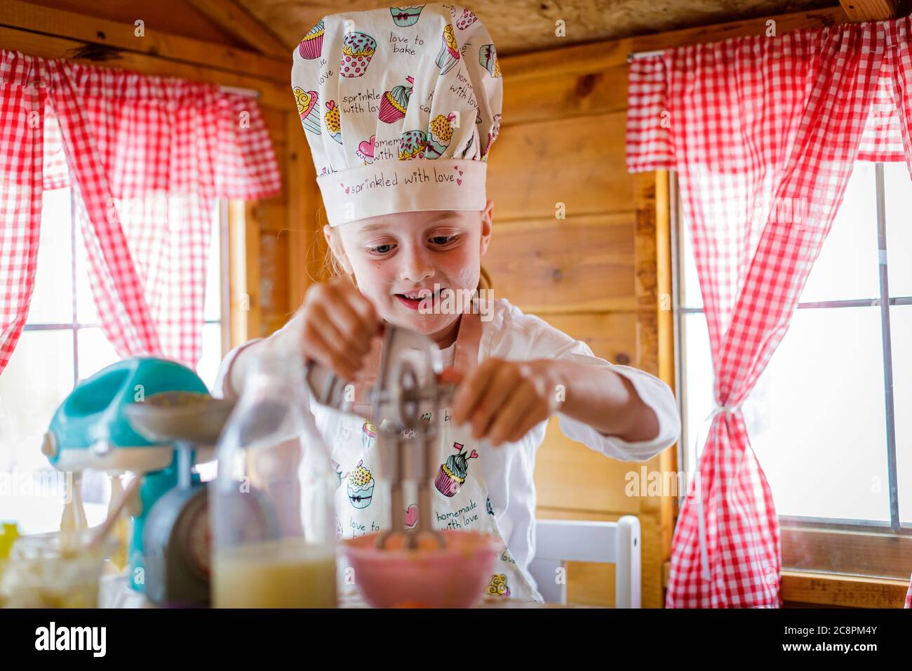 Junges Mädchen in wendy Haus mit Kunststoff Schneebesen vorgibt, in der Küche zu kochen Stockfoto