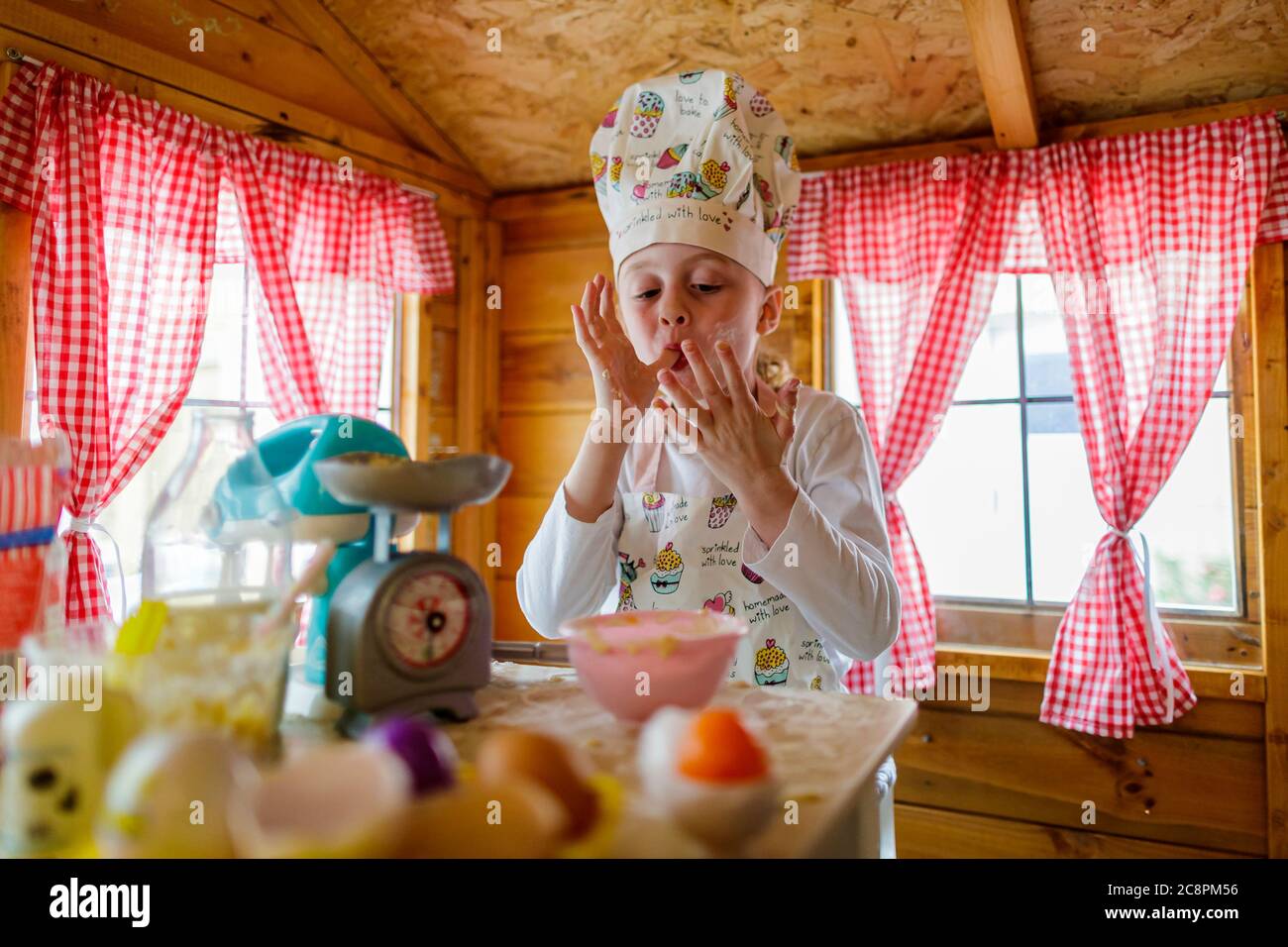Junge Mädchen in wendy Haus mögen Finger vorgeben, in der Küche zu kochen Stockfoto