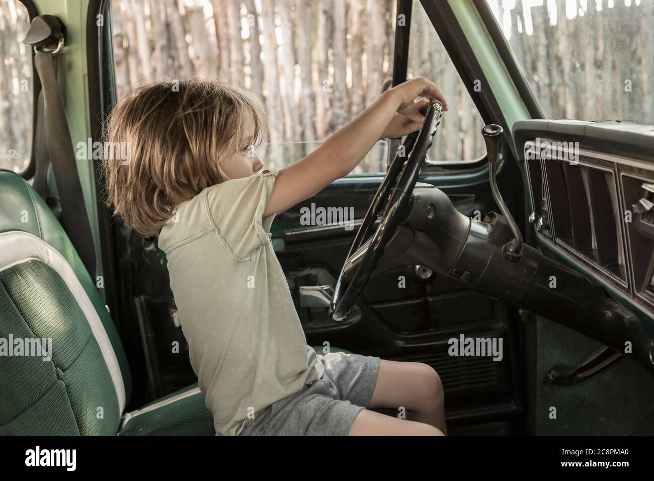 5 Jahre alter Junge hinter dem Steuer des 70er Jahre Pick-up-LKW, NM. Stockfoto