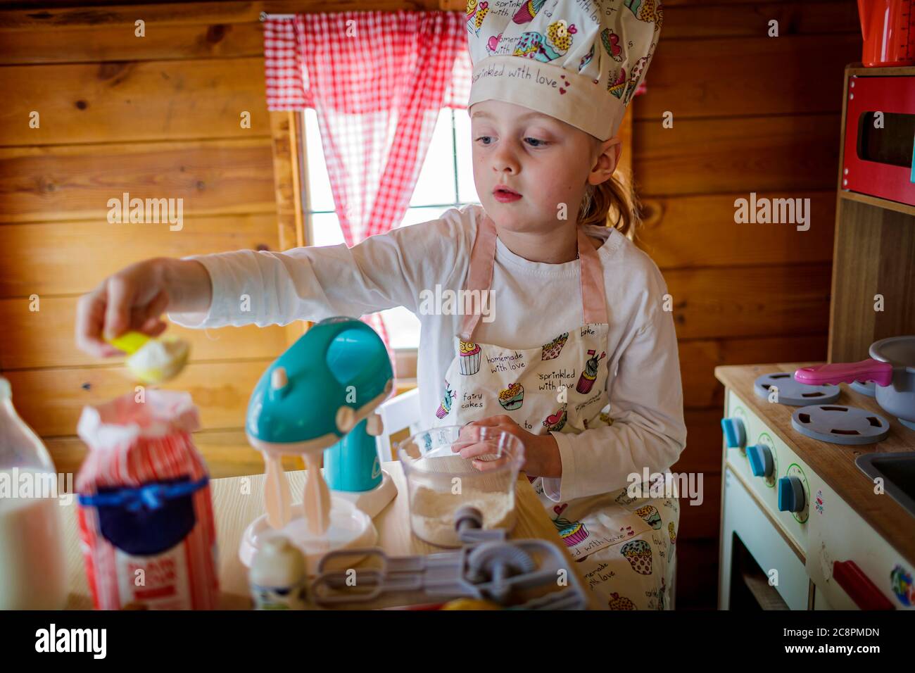 Junges Mädchen in wendy Haus vorgibt, in der Küche zu kochen Stockfoto
