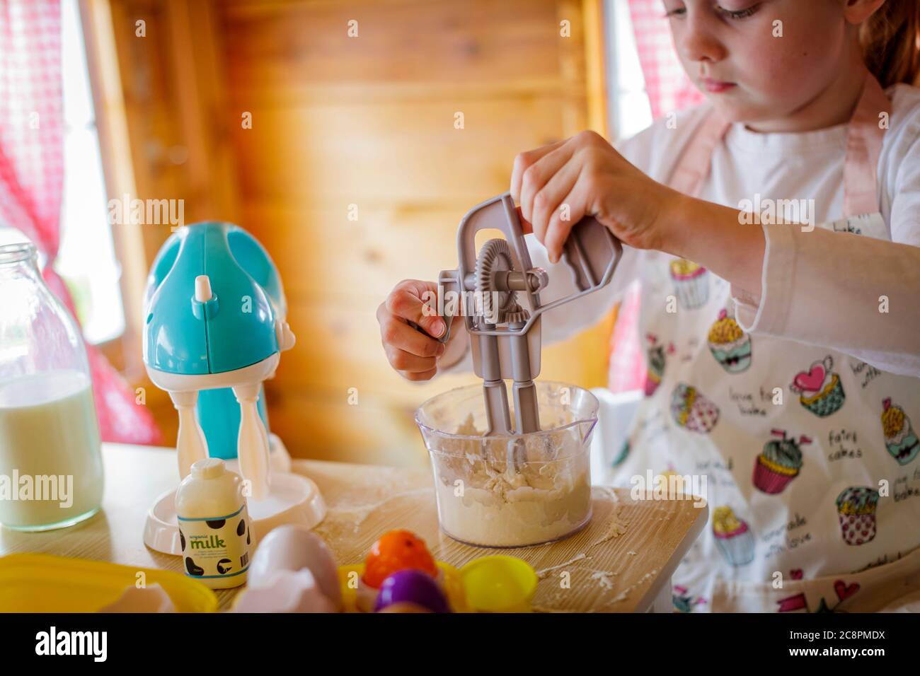 Junges Mädchen in wendy Haus mit Spielzeug Schneebesen vorgibt, in der Küche zu kochen Stockfoto