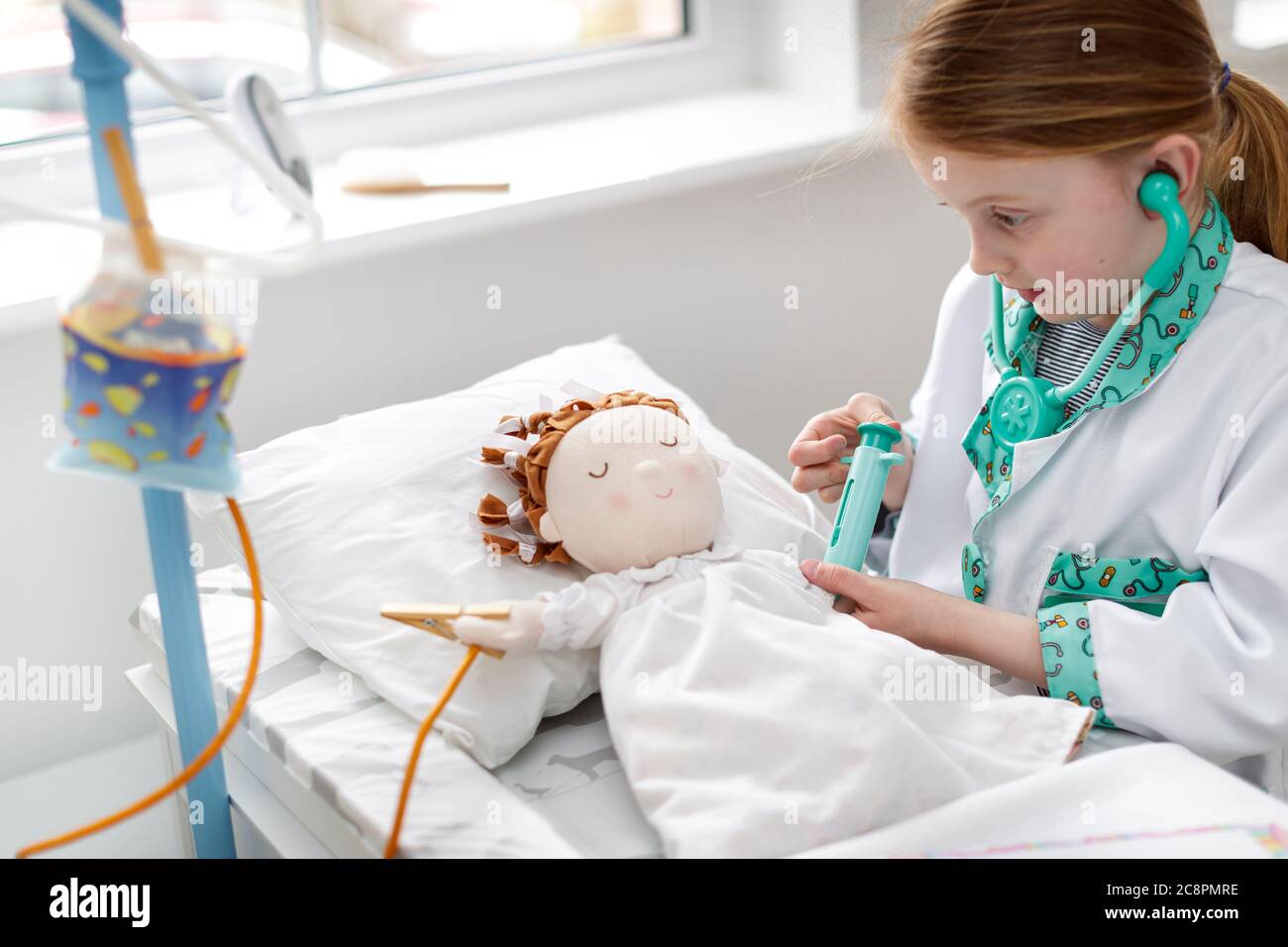 Junges Mädchen als Arzt gekleidet vorgibt, Patienten in Make-believe Krankenhaus Bett zu behandeln Stockfoto