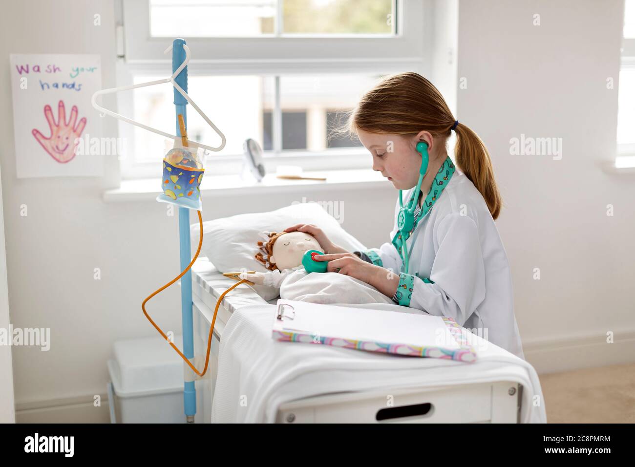 Junges Mädchen als Arzt gekleidet vorgibt, Patienten in Make-bleive Krankenhaus Bett zu behandeln Stockfoto