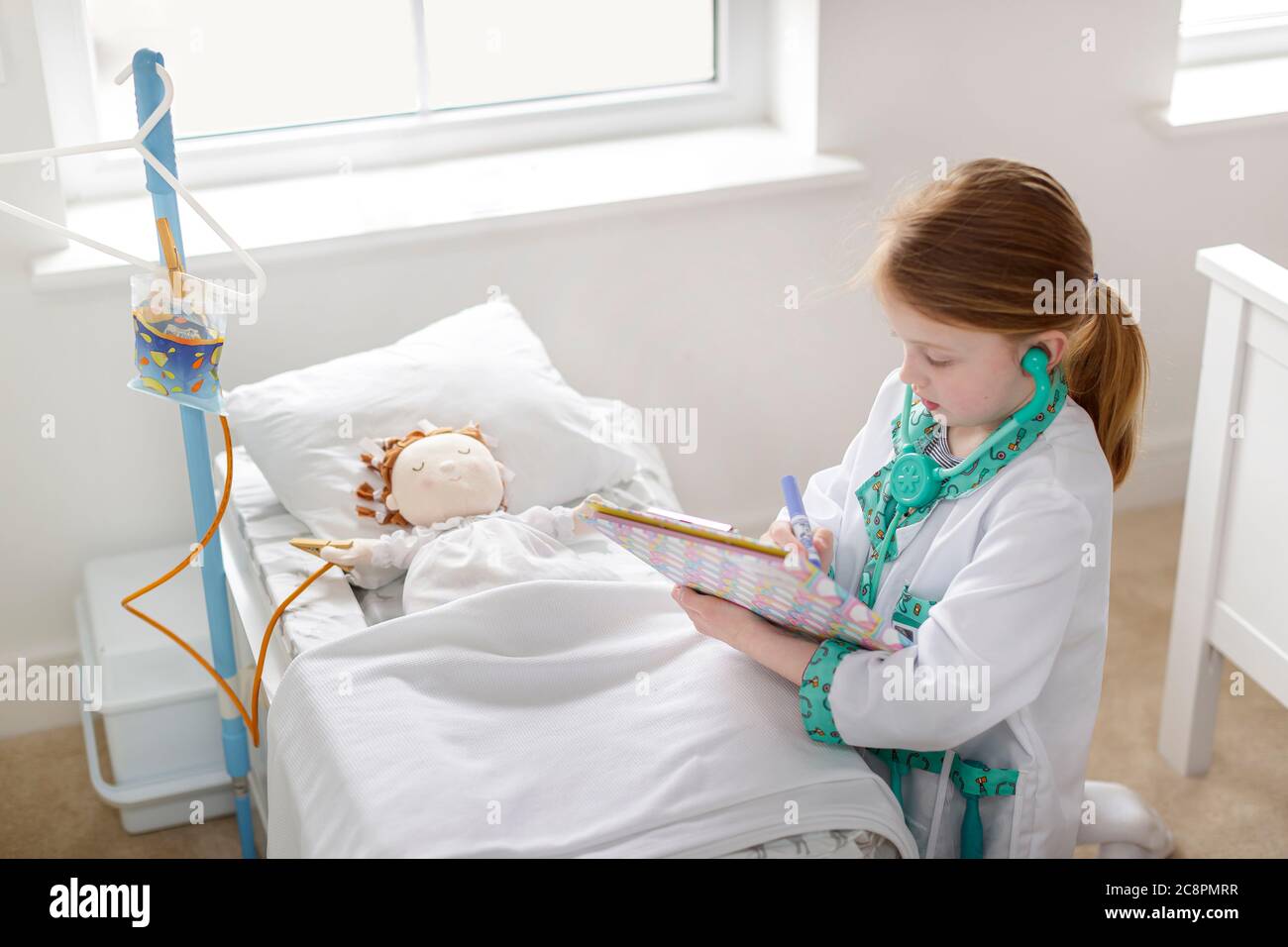 Junges Mädchen als Arzt gekleidet Schreiben Notizen neben Patienten in Make-glauben Krankenhaus Bett vorgeben Stockfoto