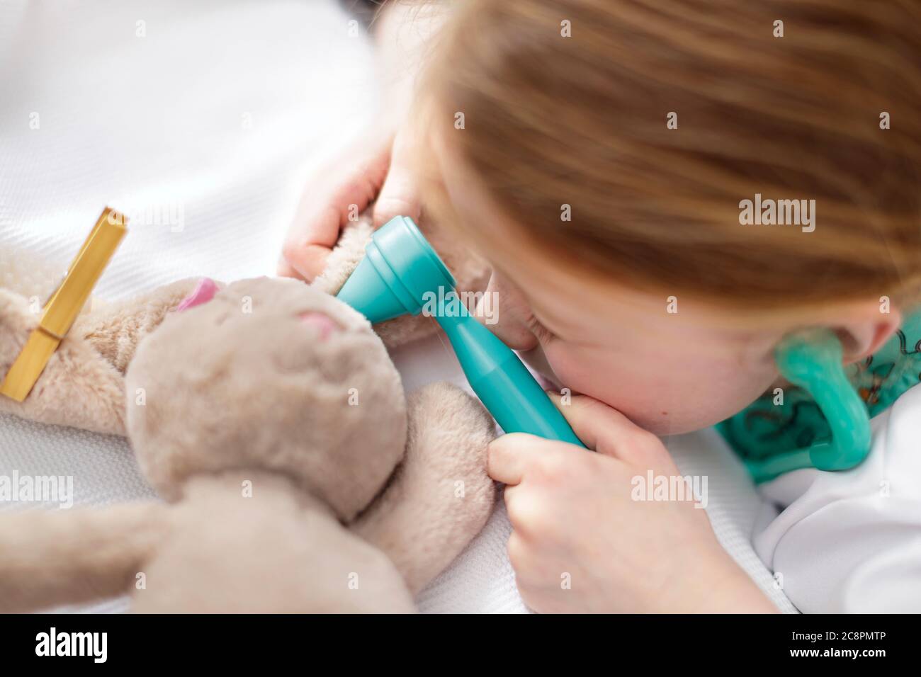Junges Mädchen als Arzt gekleidet vorgibt Spielzeug Tier in Make-believe Krankenhaus Bett zu behandeln Stockfoto
