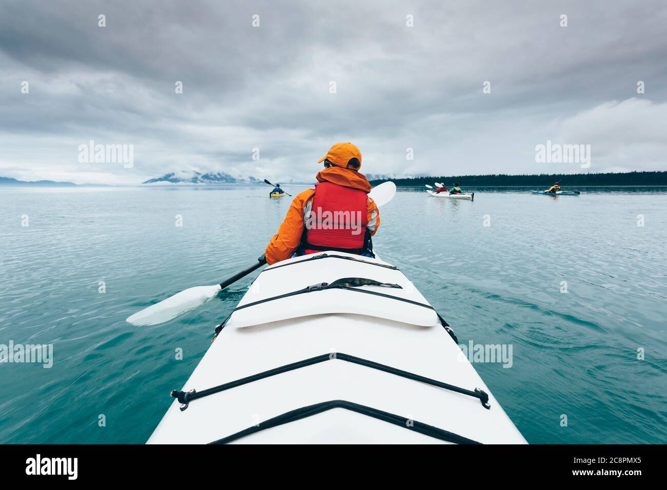 Eine Person, die in einem Doppelseekajak auf ruhigem Wasser vor der Küste Alaskas paddelt. Stockfoto