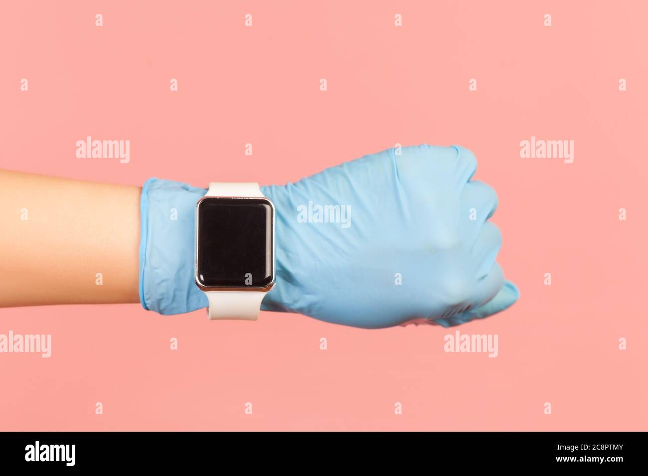 Profil Seitenansicht Nahaufnahme der menschlichen Hand in blauen OP-Handschuhe halten und zeigen wirst smart watch screen. Indoor, Studio-Aufnahme, isoliert auf rosa BA Stockfoto
