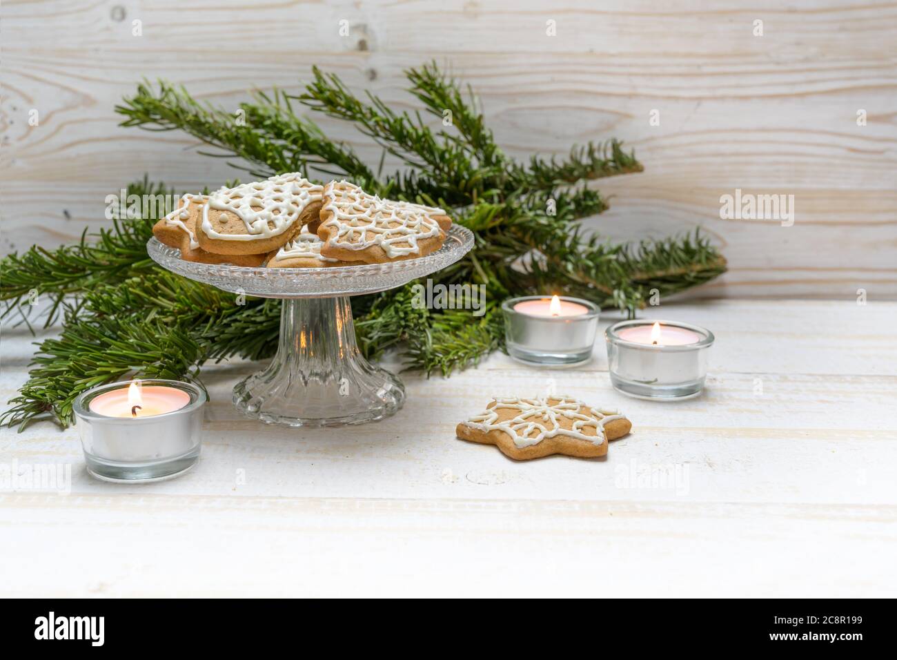 Lebkuchen zu Weihnachten auf einer Kristallglas-Schale, brennende Kerzen und Tannenzweige auf einem weiß bemalten Holztisch, Kopierraum, ausgewählte Focu Stockfoto