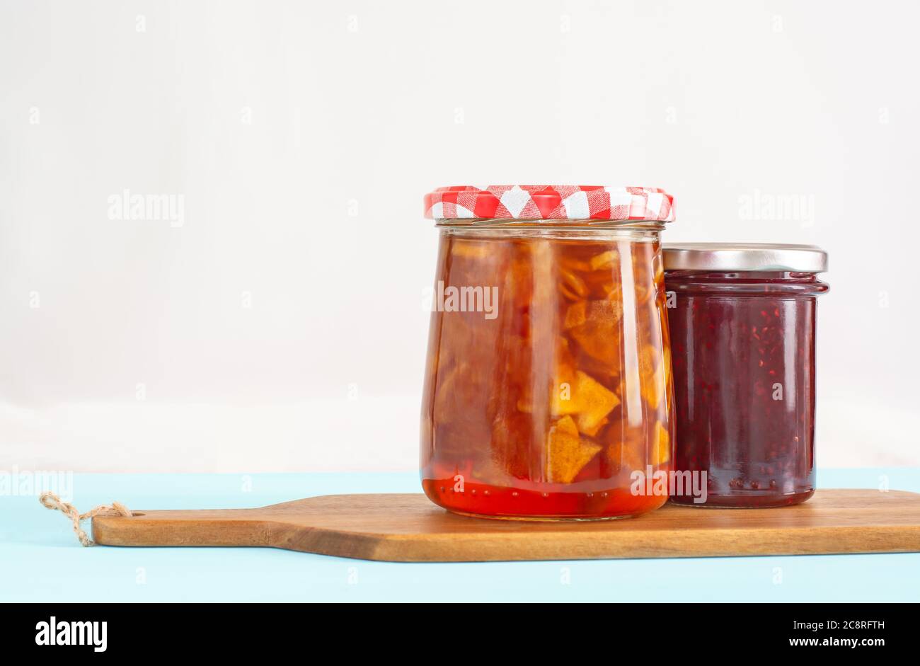 Zwei Gläser mit Apfel- und Himbeerkonfitüre auf einem Holzbrett Stockfoto