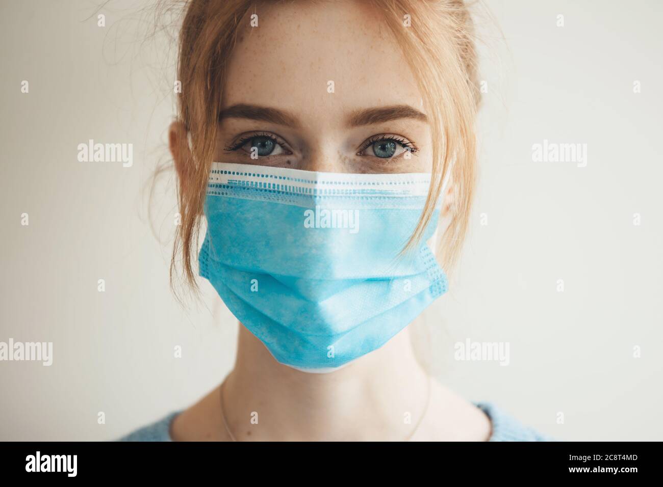 Ginger kaukasische Frau mit Sommersprossen trägt eine medizinische Maske  mit Filter posiert auf einer weißen Studiowand Stockfotografie - Alamy