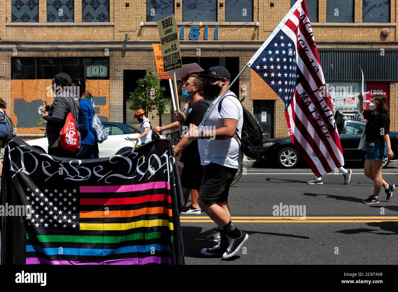 Regenbogen amerikanische Flagge, die sagt "Wir das Volk" und Protestler mit Flagge auf dem Kopf auf März gegen Trump's Police State, Washington, DC, USA Stockfoto