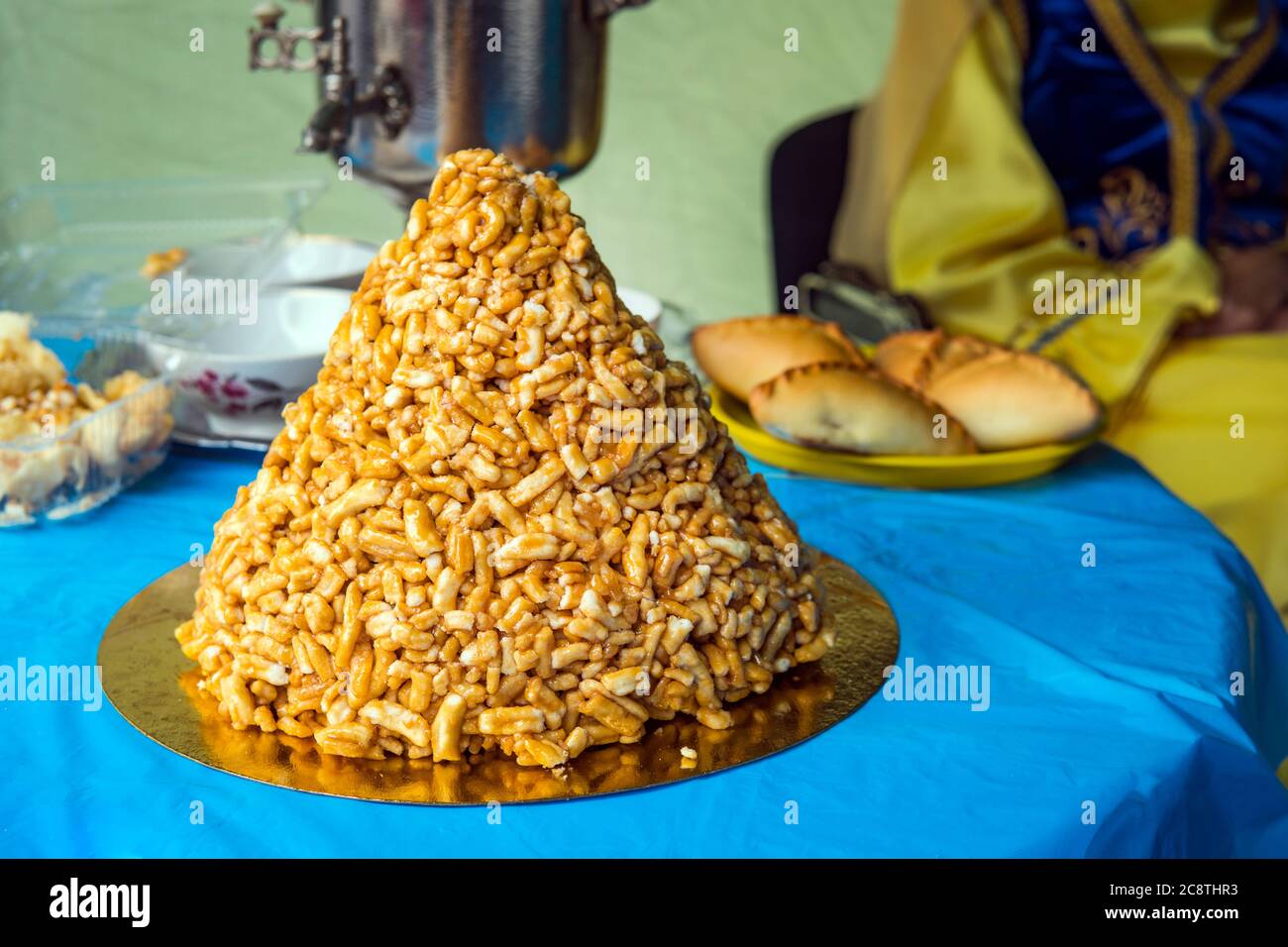 Nationalgericht Chuck auf einem blauen Tisch von einem Hügel auf dem Hintergrund von Samowar und Kuchen ausgelegt. Traditionelle östliche Teeparty. Süßigkeiten von Central Stockfoto