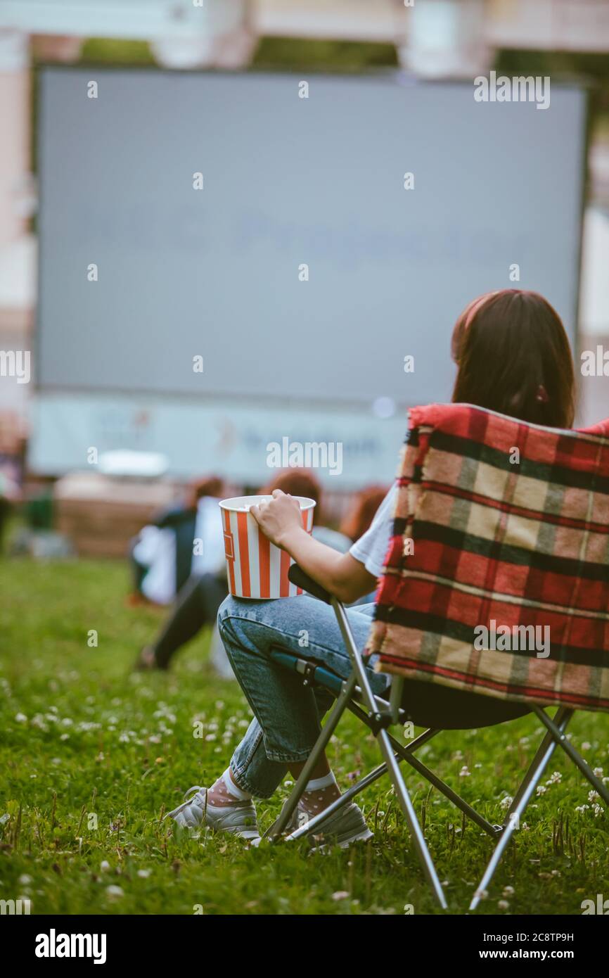 Frau, die im Campingstuhl sitzt und Film im Open Air Kino sieht Stockfoto