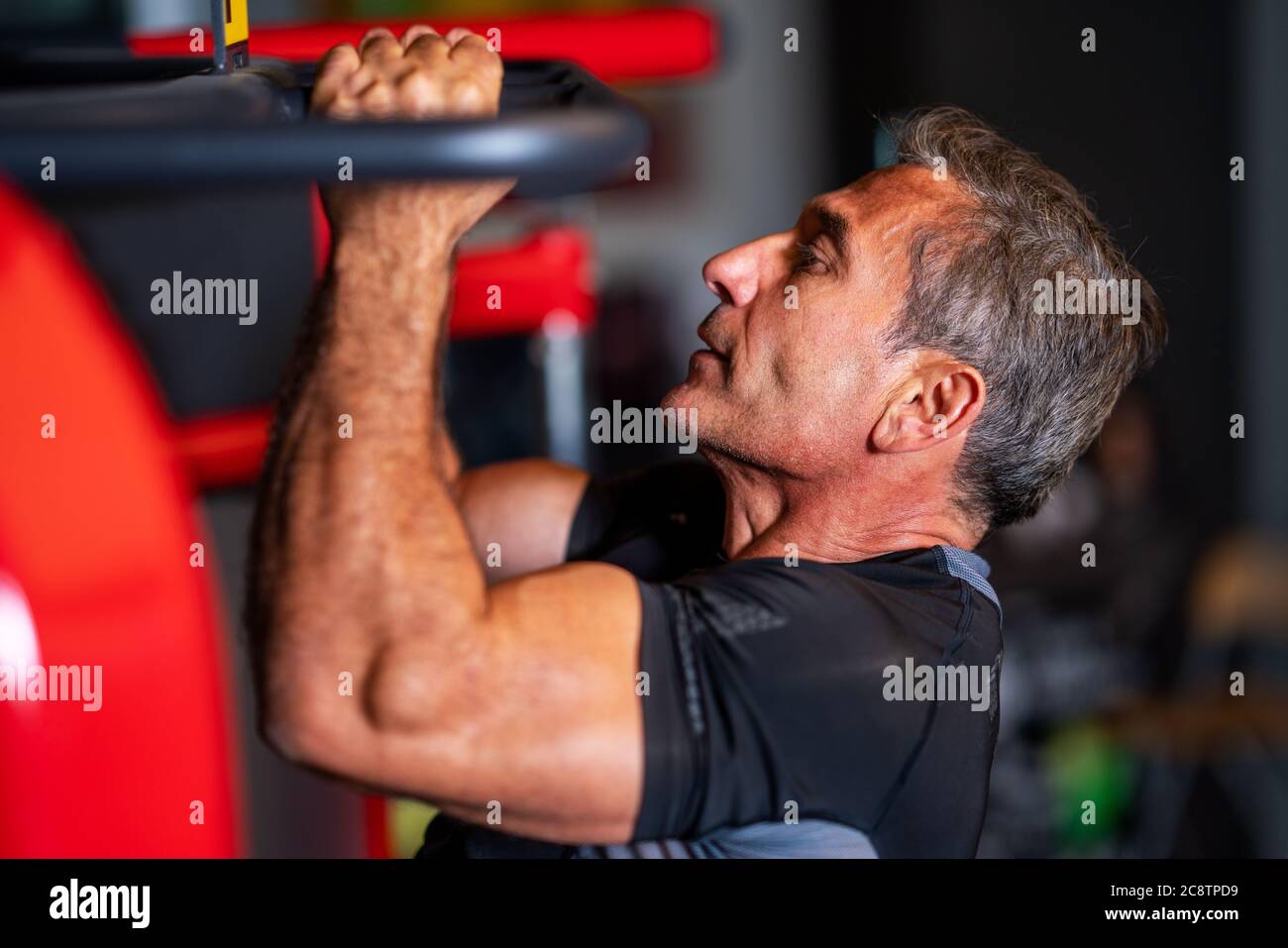 Mann stärkt seine Muskeln durch Pull-up auf horizontale Bar in einem Fitnesscenter. Hochwertige Fotos Stockfoto