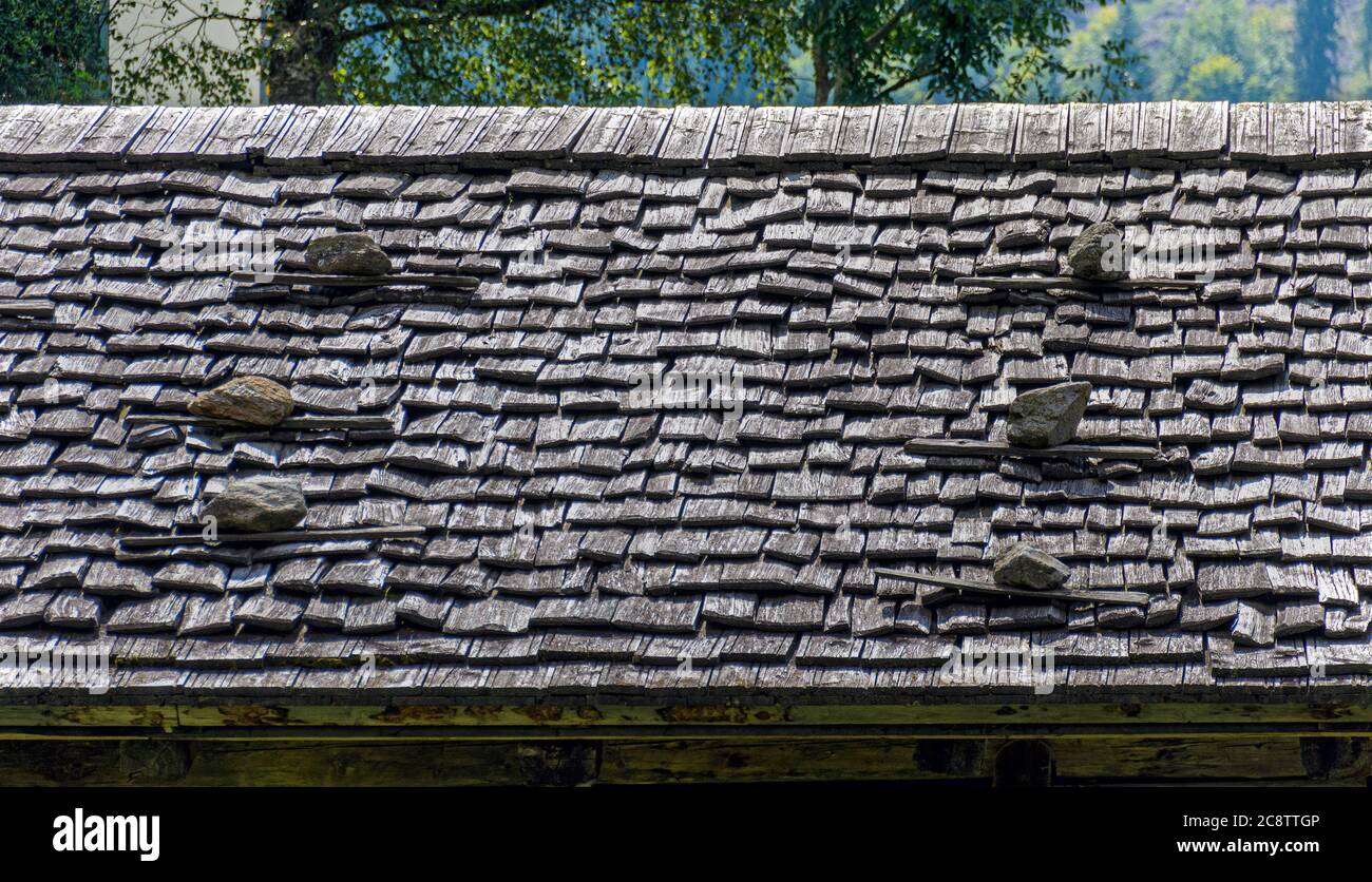 Dachdeckung aus verwitterten Holzspaltdachschindeln und Schneeschutz aus Steinen auf einem Gebäude in Tirol, Österreich Stockfoto