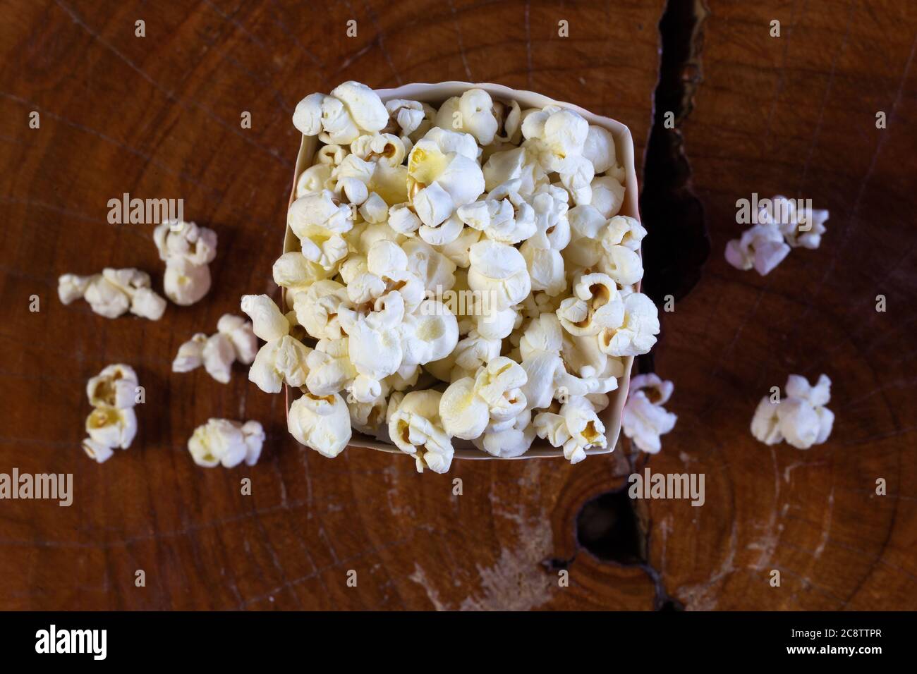 Popcorn in gestreifter retro rot-weißer Kartonschachtel für Kino auf Holztisch Stockfoto