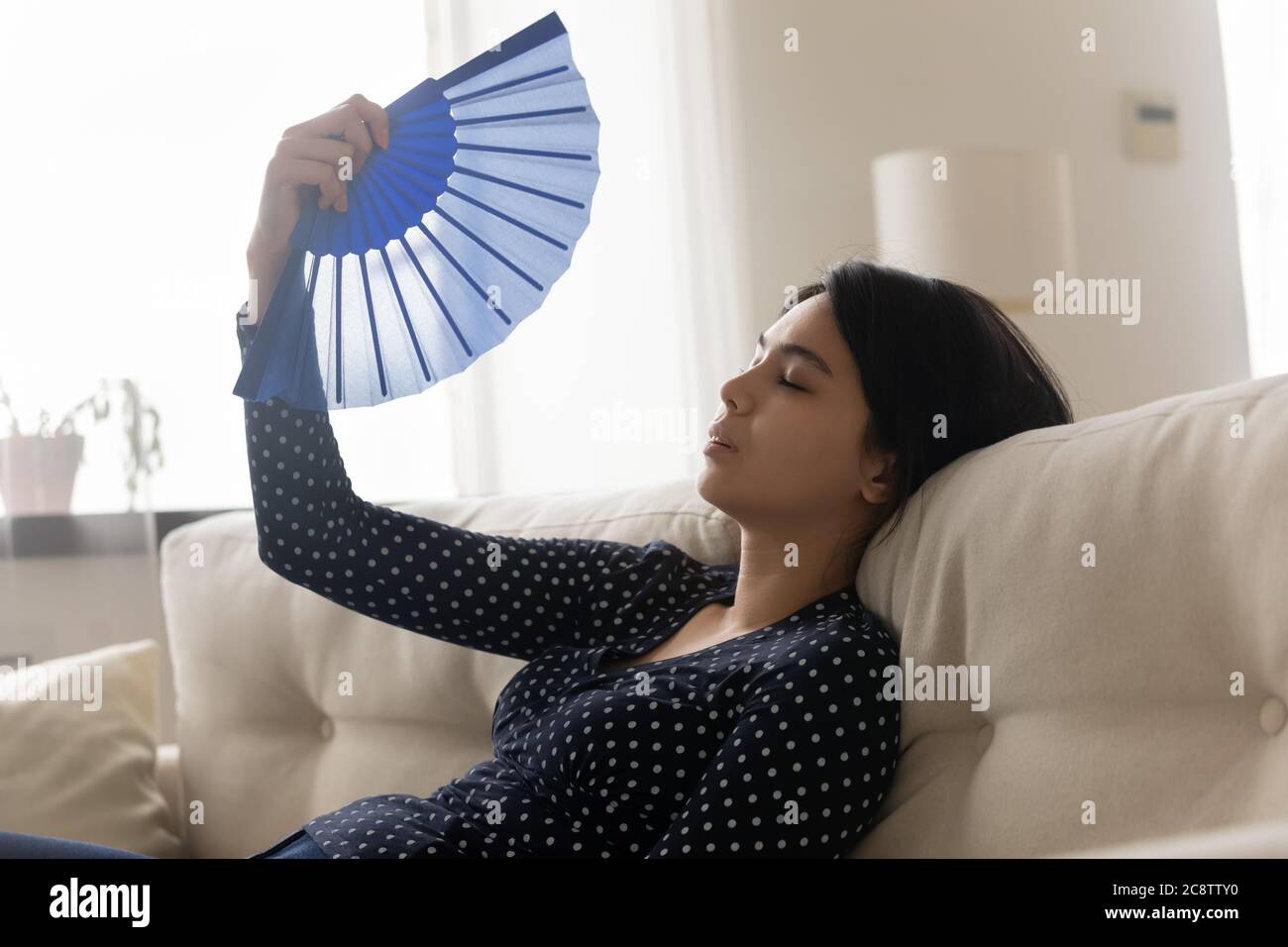 Unwell asiatische Mädchen fühlen überhitzte Welle mit Hand Fan Stockfoto