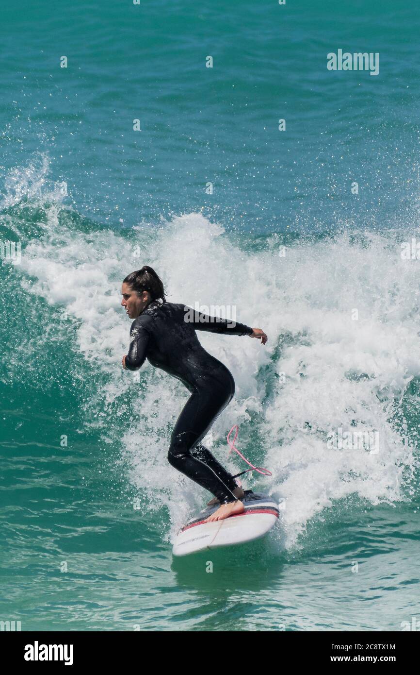 Eine Surferin reitet auf einer Welle bei Fistral in Newquay in Cornwall. Stockfoto