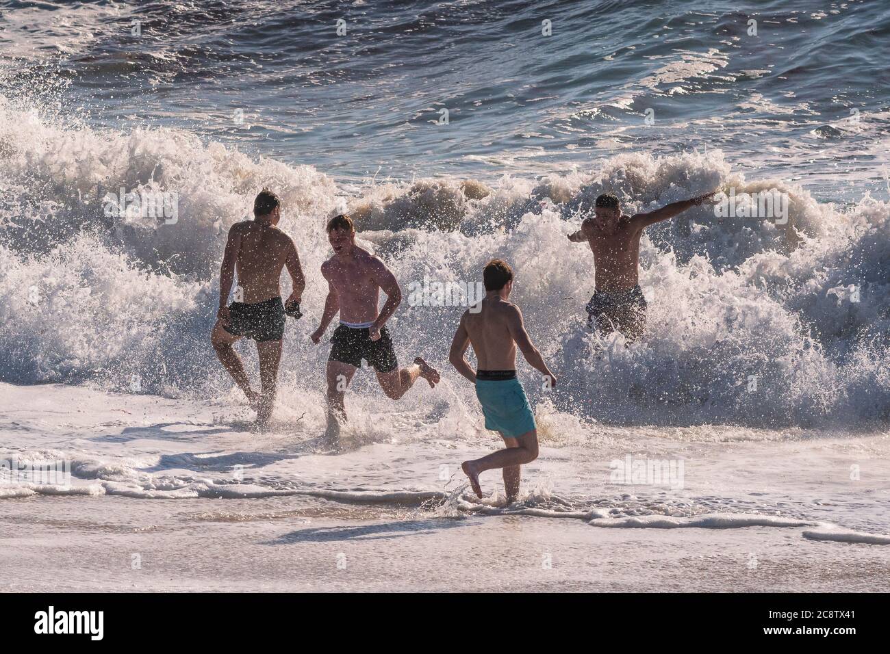 Männliche Urlauber verbringen ihren Urlaub im Meer am Fistral Beach in Newquay in Cornwall. Stockfoto