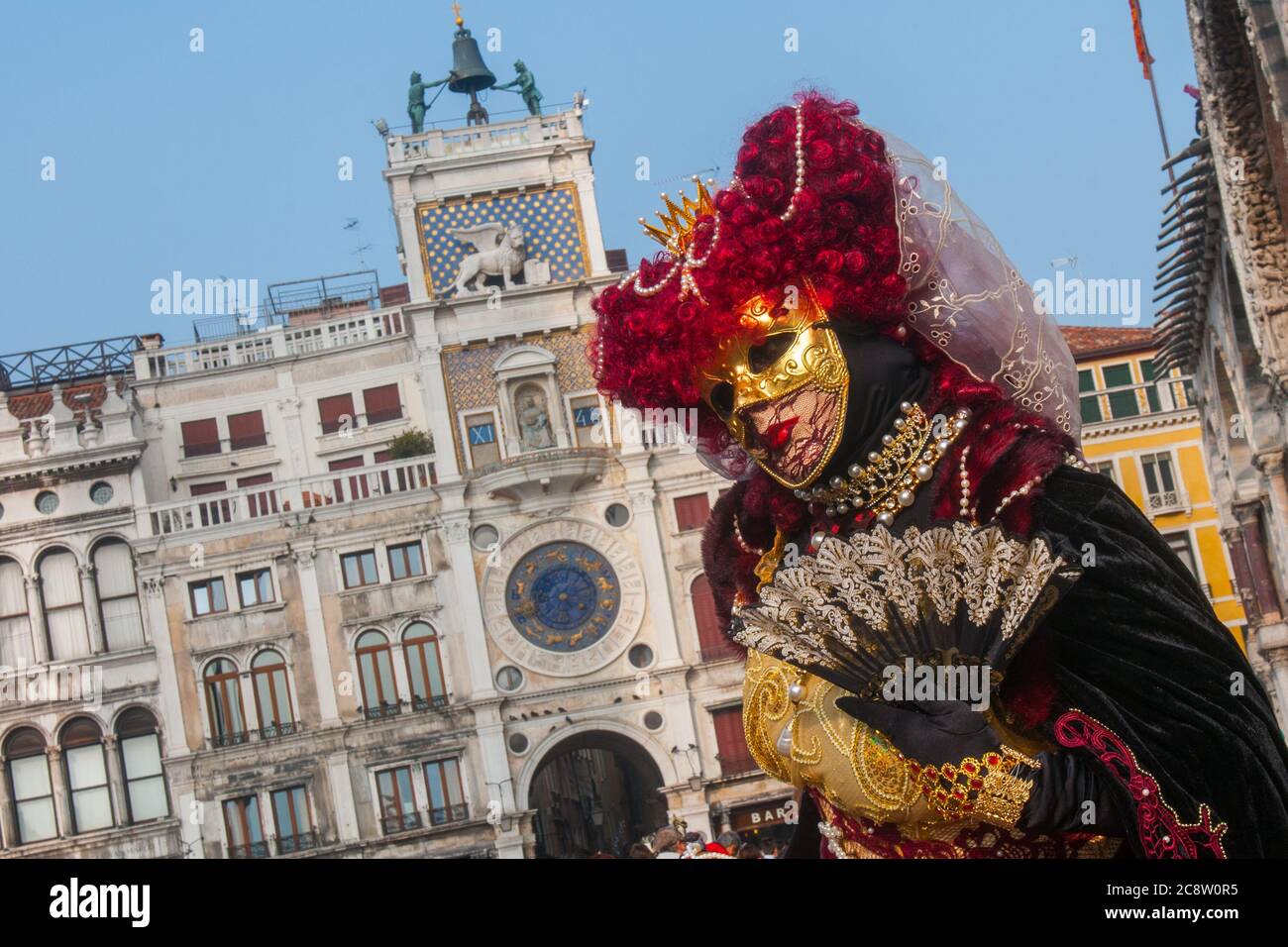 VENEDIG, ITALIEN - 28. FEBRUAR 2020: Eine wunderschöne Maske in schwarz-roten Kostümposen während des Karnevals von Venedig Stockfoto