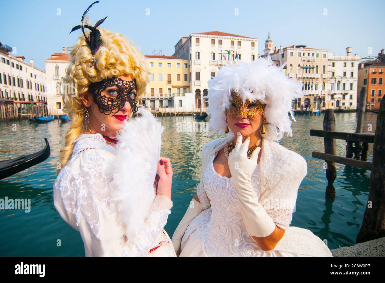 VENEDIG, ITALIEN - 28. FEBRUAR 2020: Zwei weiße Dames mit Maske posiert vor einem Venedig-Kanal. Stockfoto