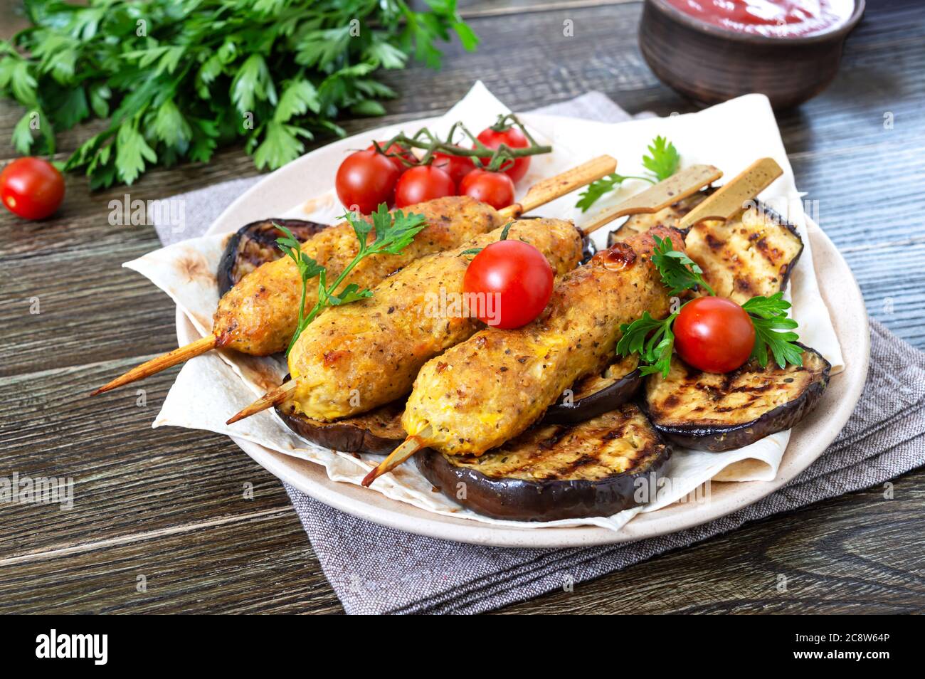 Lula Kebab mit gegrillter Aubergine auf Pita-Brot. Diätetische Hühnerkebabs auf einem Spieß mit Gemüse. Stockfoto