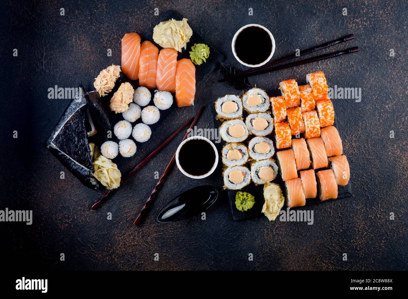 Leckere Sushi-Brötchen mit Soßen, Ingwer und Wasabi auf dunkel Stockfoto