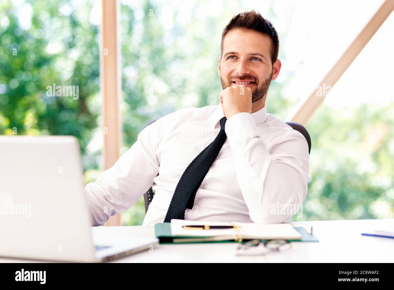 Erfolgreicher Geschäftsmann trägt ein Hemd und Krawatte, während er am Schreibtisch sitzt und arbeitet. Stockfoto