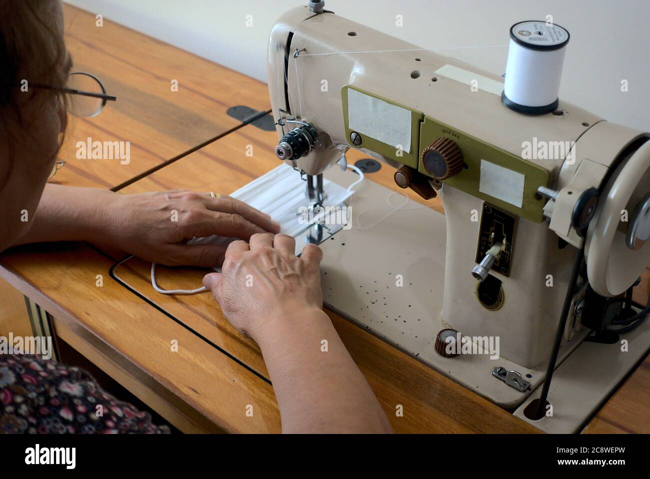 Nahaufnahme Frau Herstellung chirurgische Maske mit einer Nähmaschine - Schulteransicht Stockfoto