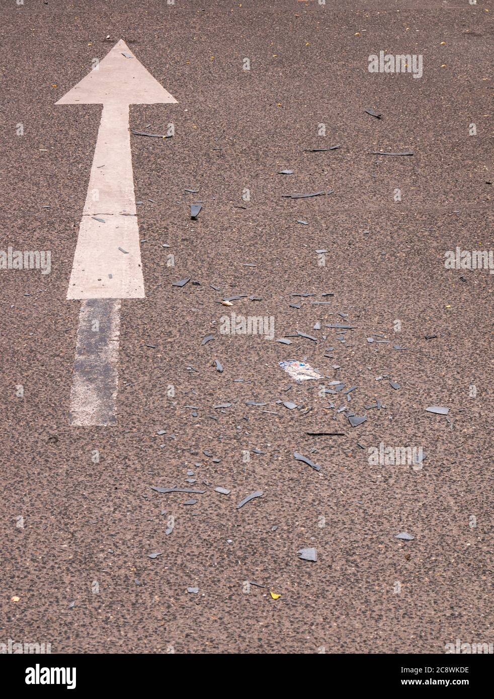 Asphaltstraße mit Pfeil und geknackten Kunststoffen von Autos Stockfoto